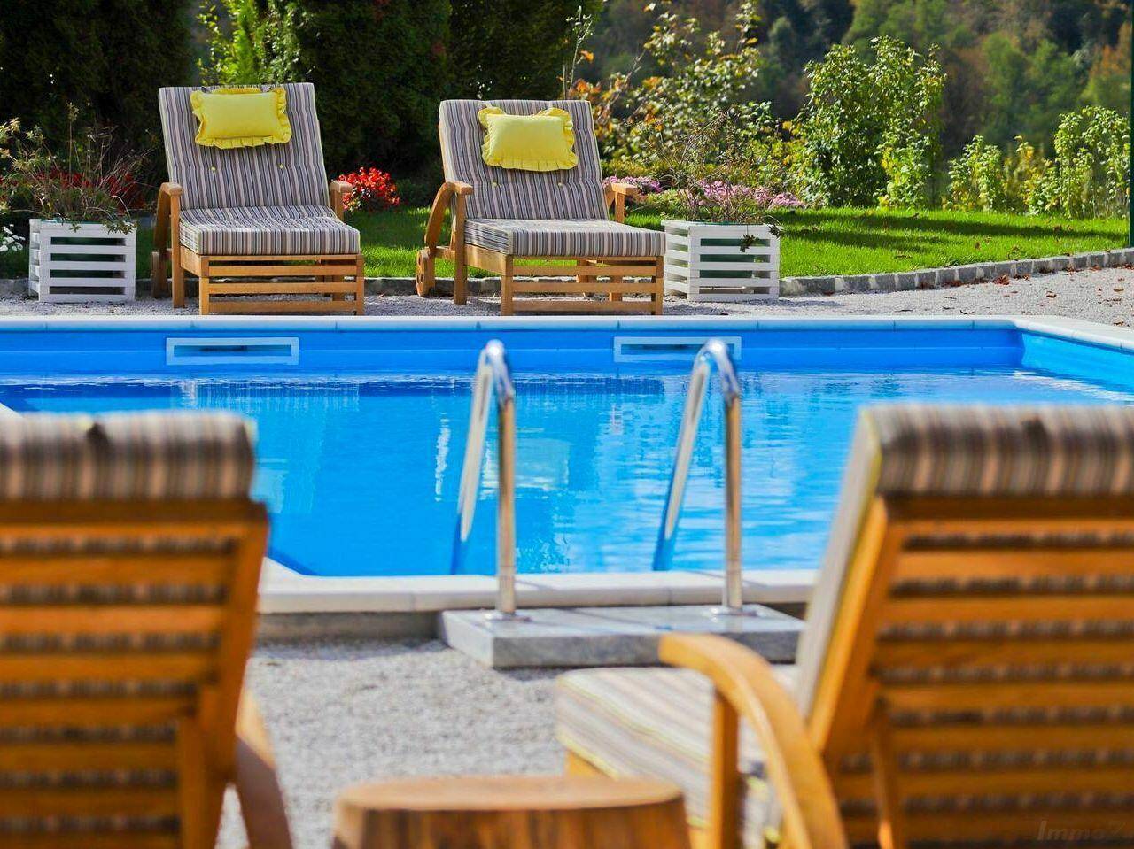Entspannungsbereich am Pool mit bequemen Liegestühlen und Blick ins Grüne.