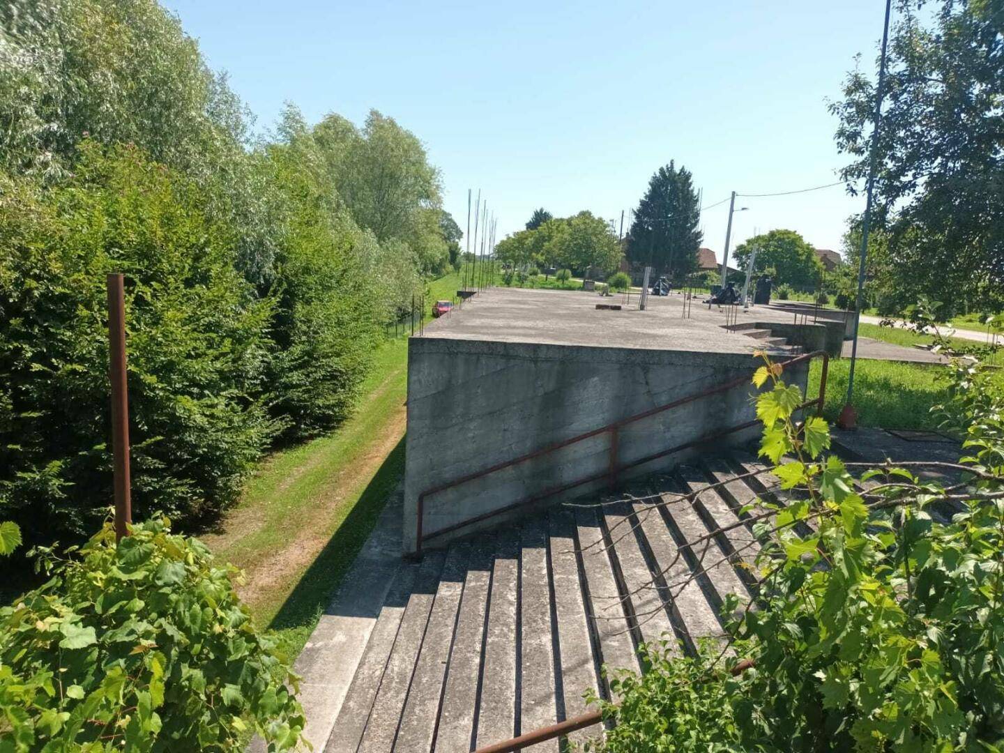 Breite Betontreppe führt zu einer erhöhten Plattform, umgeben von grüner Vegetation.