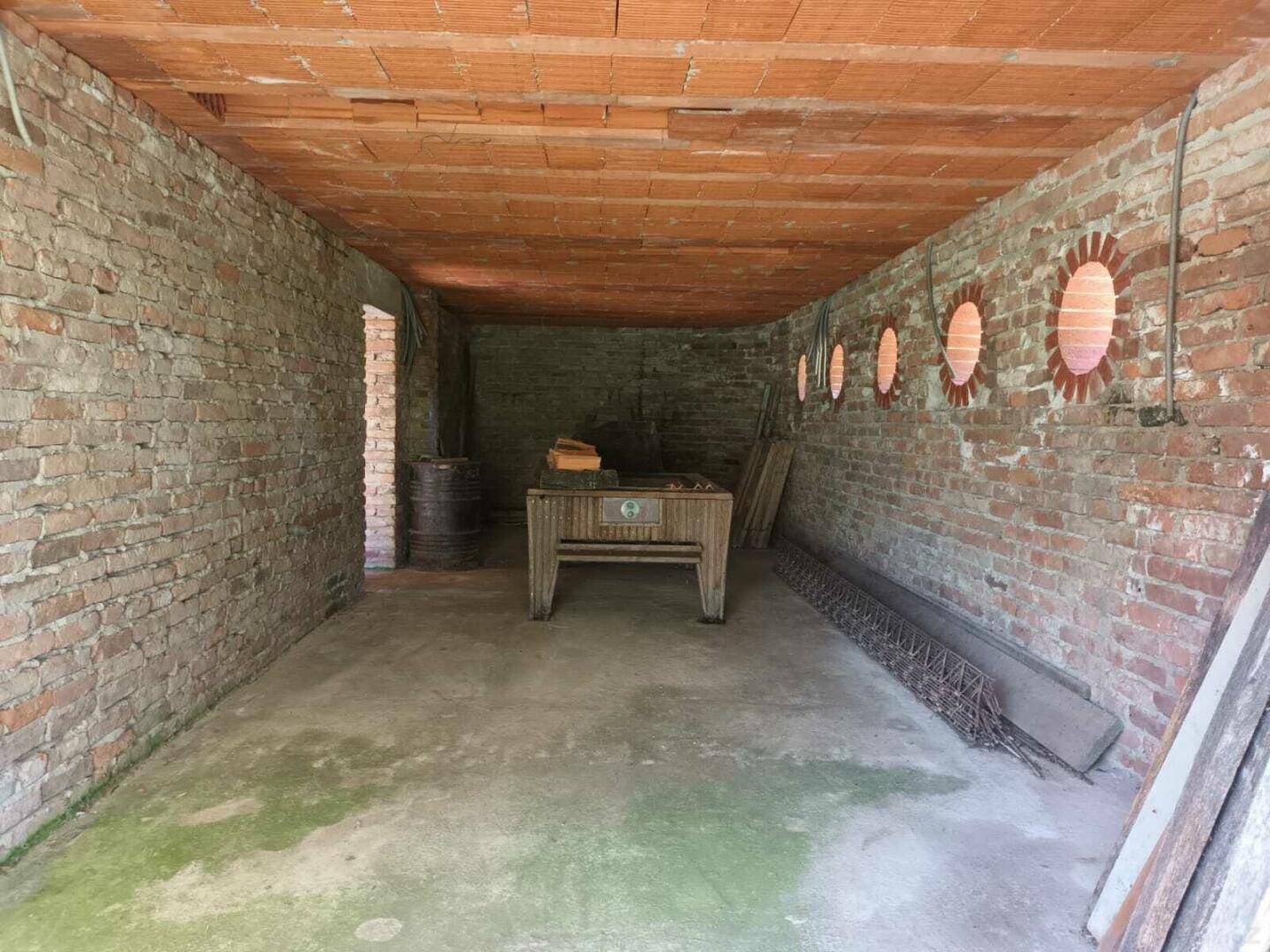 Unfertiger Kellerraum mit unverputzten Ziegelwänden und Betonboden, genutzt als Lagerfläche.