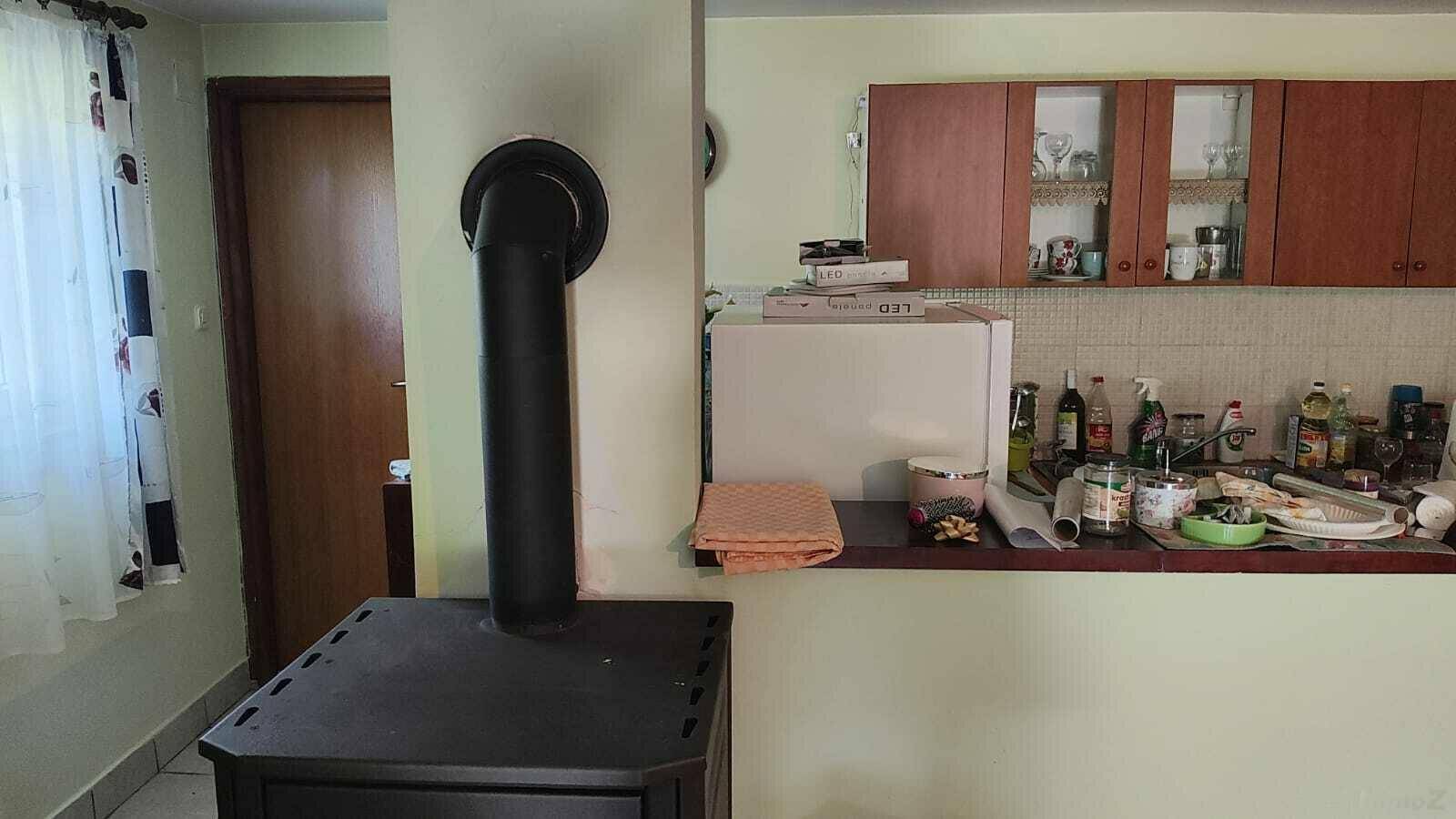 Küchenzeile mit Arbeitsplatte, Kühlschrank und Holzofen im Vordergrund.