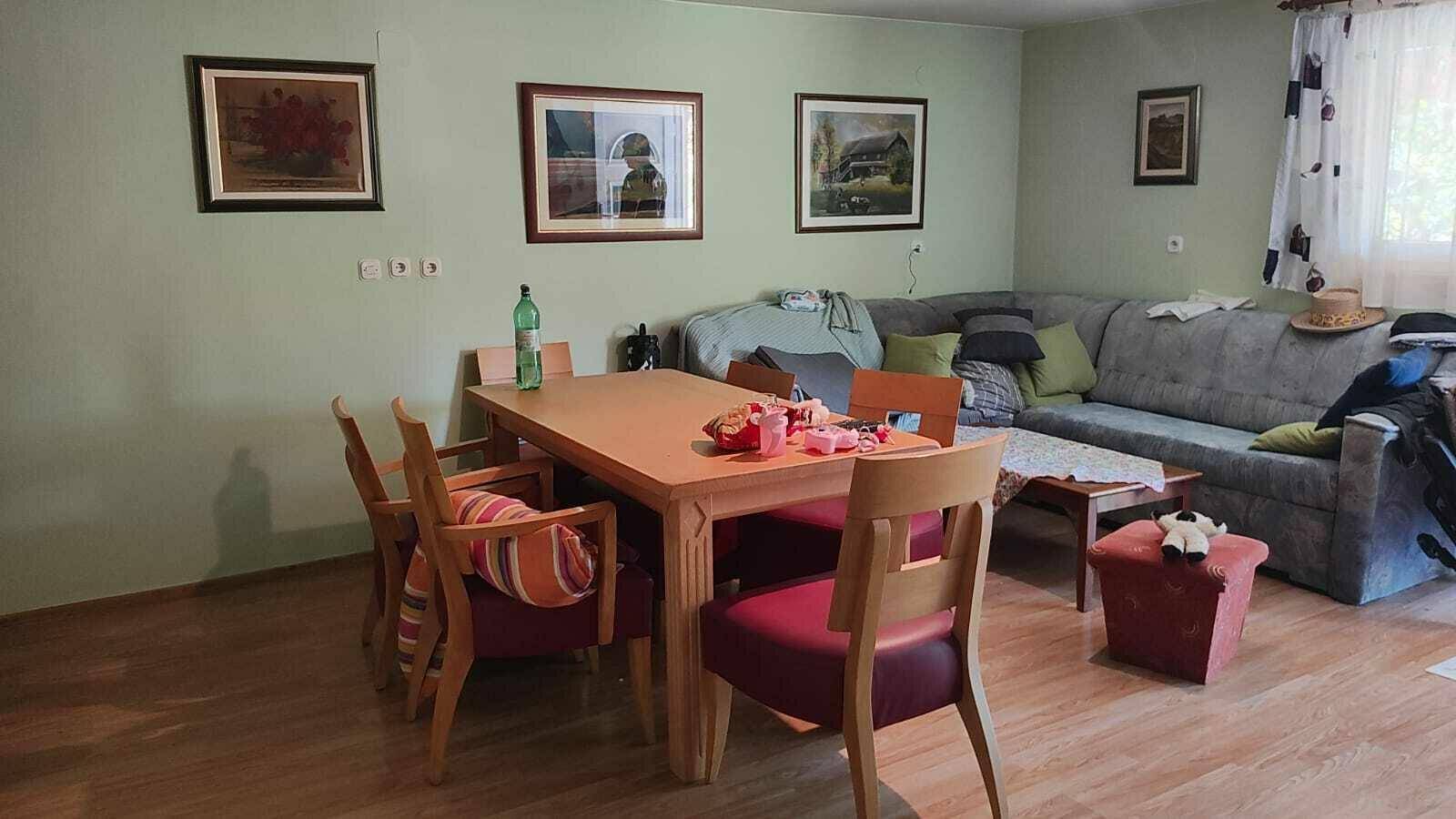 Gemütlicher Wohn-Essbereich mit Esstisch, Sofa und Bildern an hellgrünen Wänden.