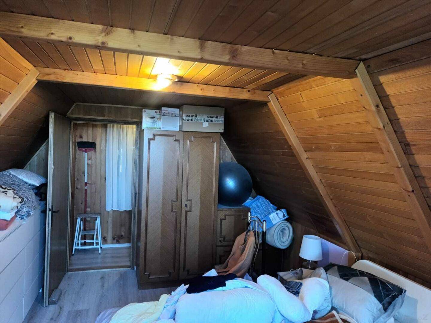 Dachgeschosszimmer mit Holzvertäfelung, schrägen Wänden und Stauraum.