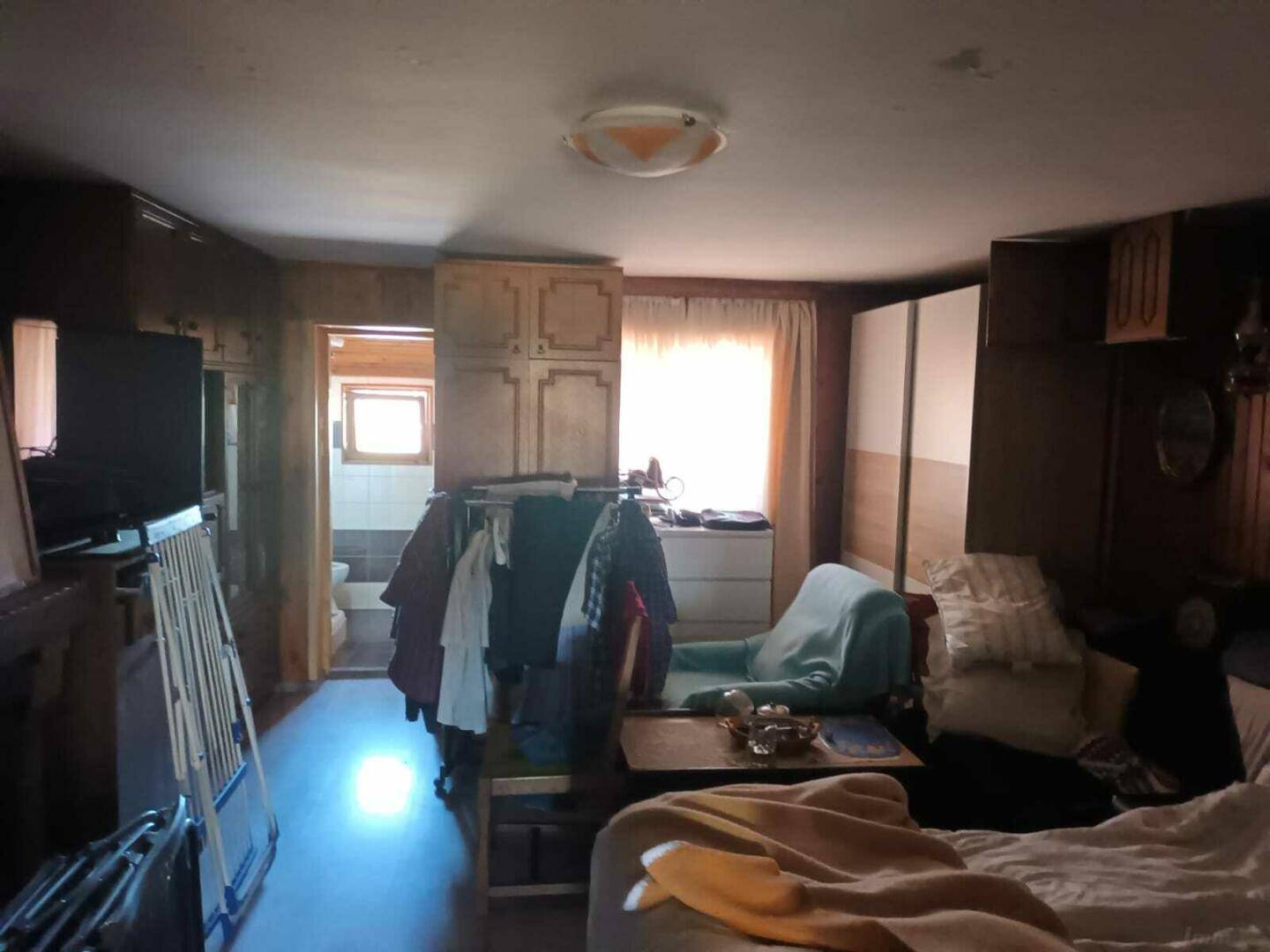 Gemütliches Schlafzimmer mit Holzvertäfelung, Kleiderschränken und Zugang zu einem Badezimmer.