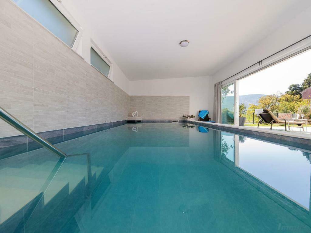 Geräumiger Innenpoolbereich mit großen Fenstern, die viel Tageslicht hereinlassen.