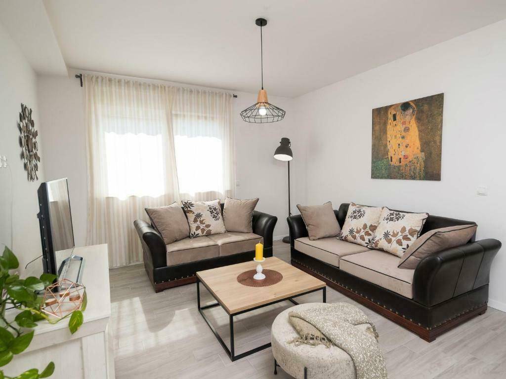 Helles Wohnzimmer mit bequemen Sofas, Couchtisch und einem modernen Stehlampen-Design.
