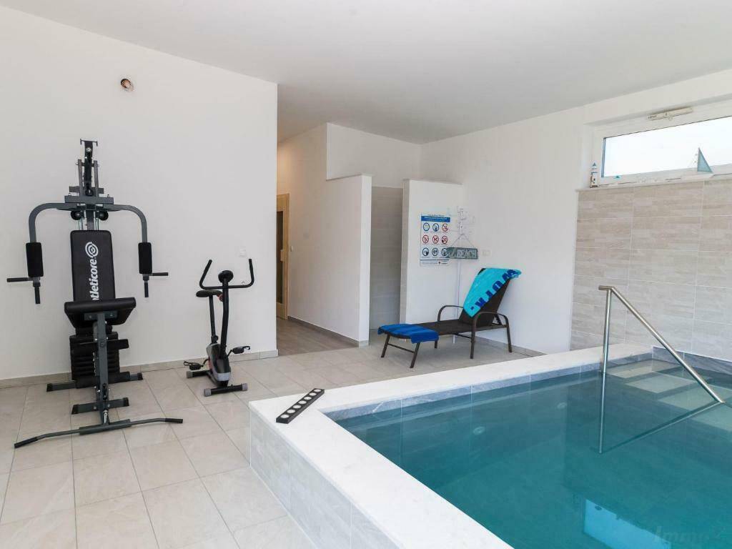 Fitnessbereich mit Trainingsgeräten und einem beheizten Innenpool für Sport und Entspannung.