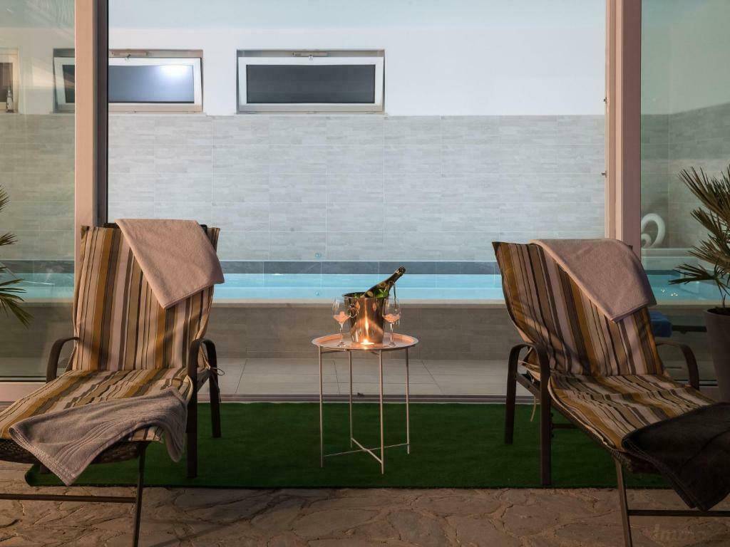 Abendliche Terrasse mit Liegestühlen und Blick auf den beleuchteten Innenpoolbereich.