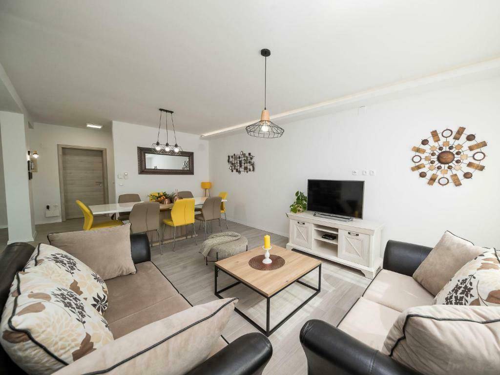 Geräumiger Wohn- und Essbereich mit beigen Sofas, Couchtisch und dekorativen Wandelementen.