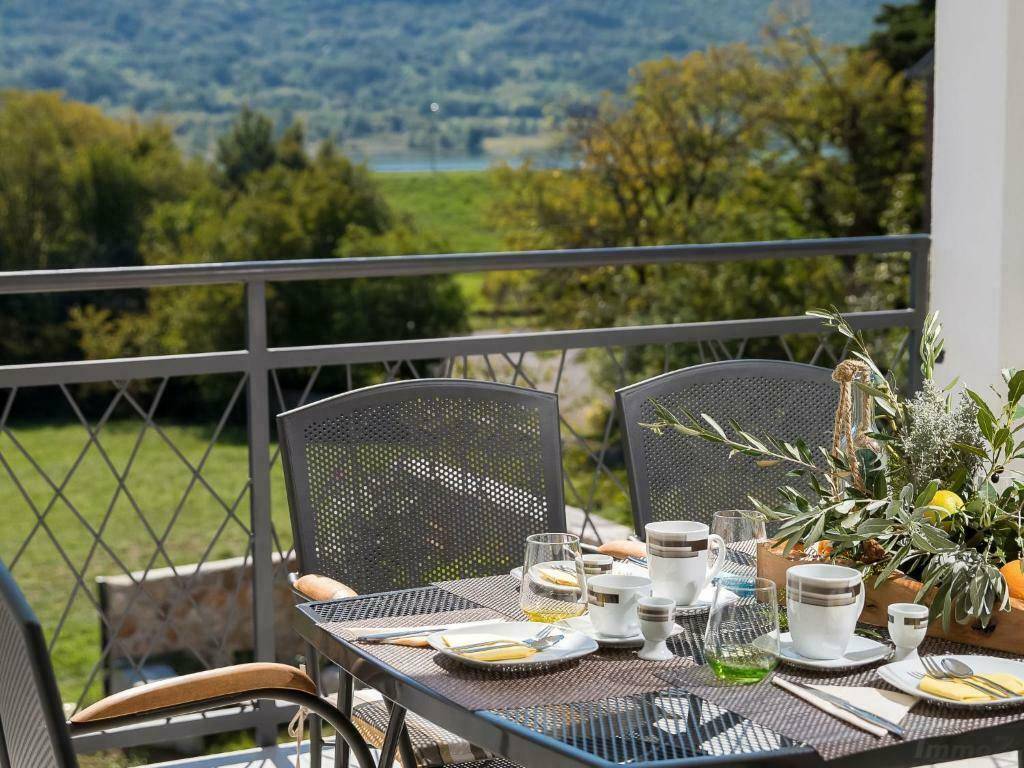 Gemütlicher Balkon mit Esstisch und Stühlen, bietet einen malerischen Blick auf die grüne Landschaft.