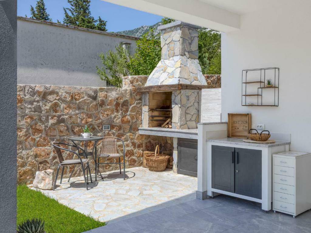 Gemütlicher Grillbereich im Freien mit Steingrill und kleinem Esstisch, umgeben von einer Steinmauer.