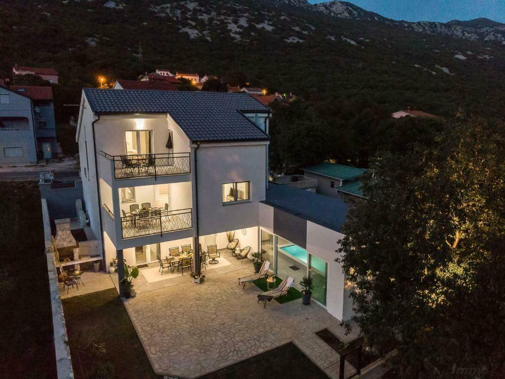 Beleuchtete Terrasse mit Pool und gemütlichen Sitzbereichen am Abend, umgeben von Bergen.
