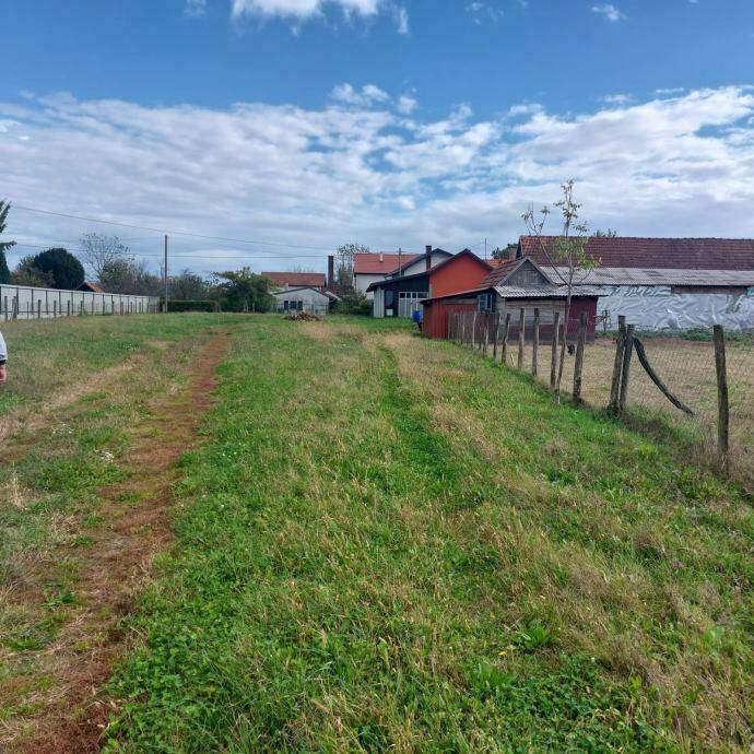 Weitläufiges Grundstück mit Grasfläche und Zaun, angrenzend an weitere Gebäude.