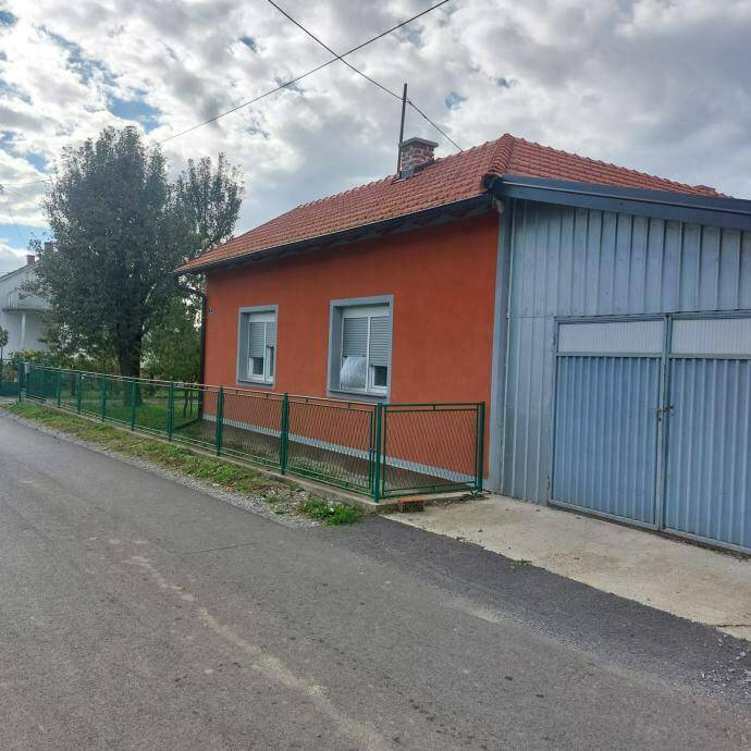 Seitenansicht des Hauses mit orangefarbener Fassade, Ziegeldach und angrenzender Garage.