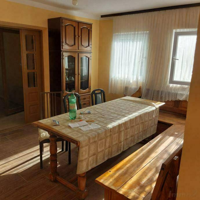 Geräumiges Esszimmer mit großem Holztisch, Sitzbänken und einem Vitrinenschrank.