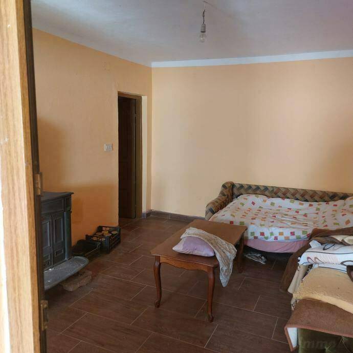 Gemütliches Wohnzimmer mit Kaminofen, Fliesenboden und einfacher Einrichtung.