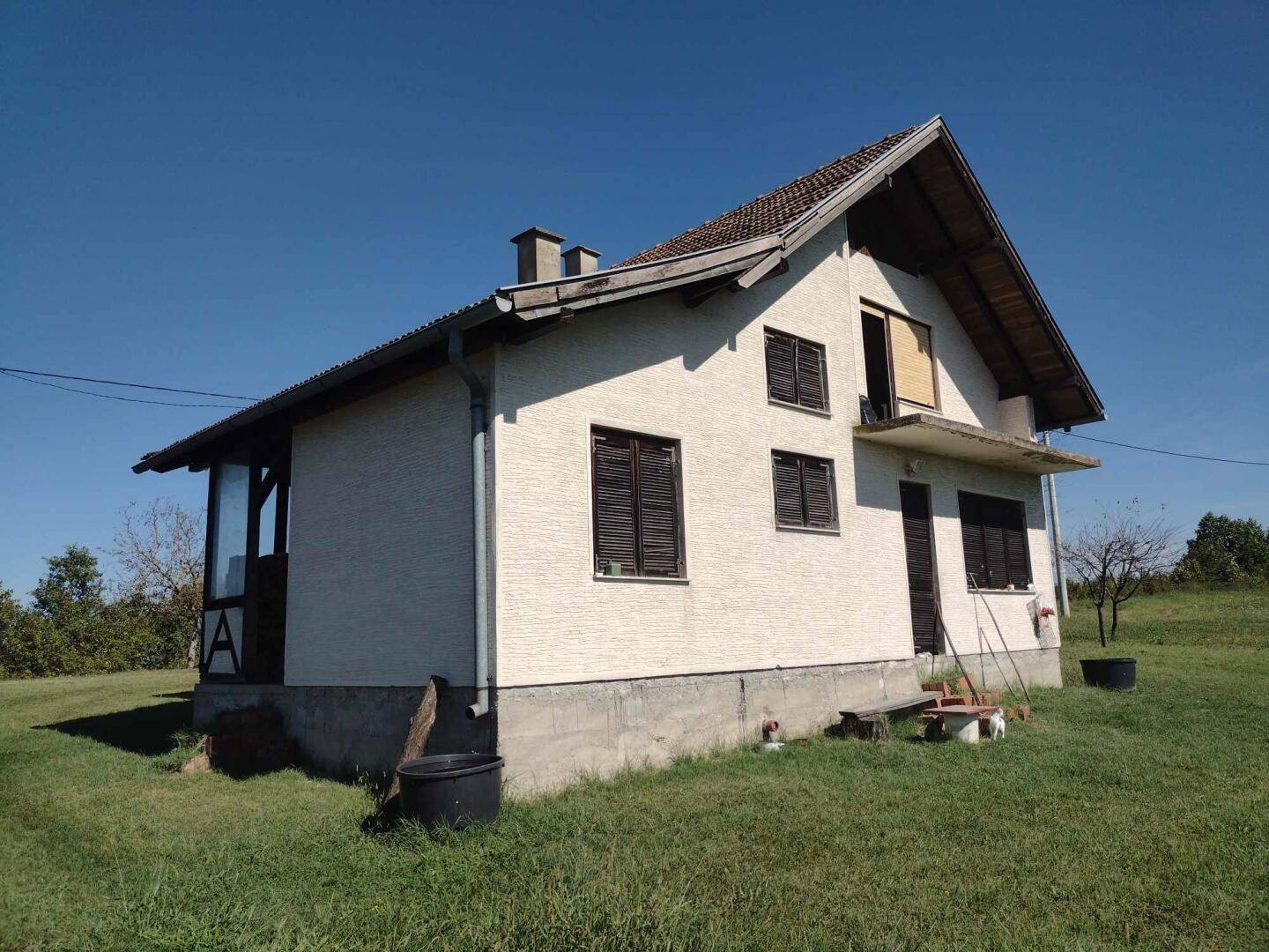 Freistehendes Wohnhaus mit traditionellem Satteldach und Fensterläden, eingebettet in eine ländliche Umgebung.