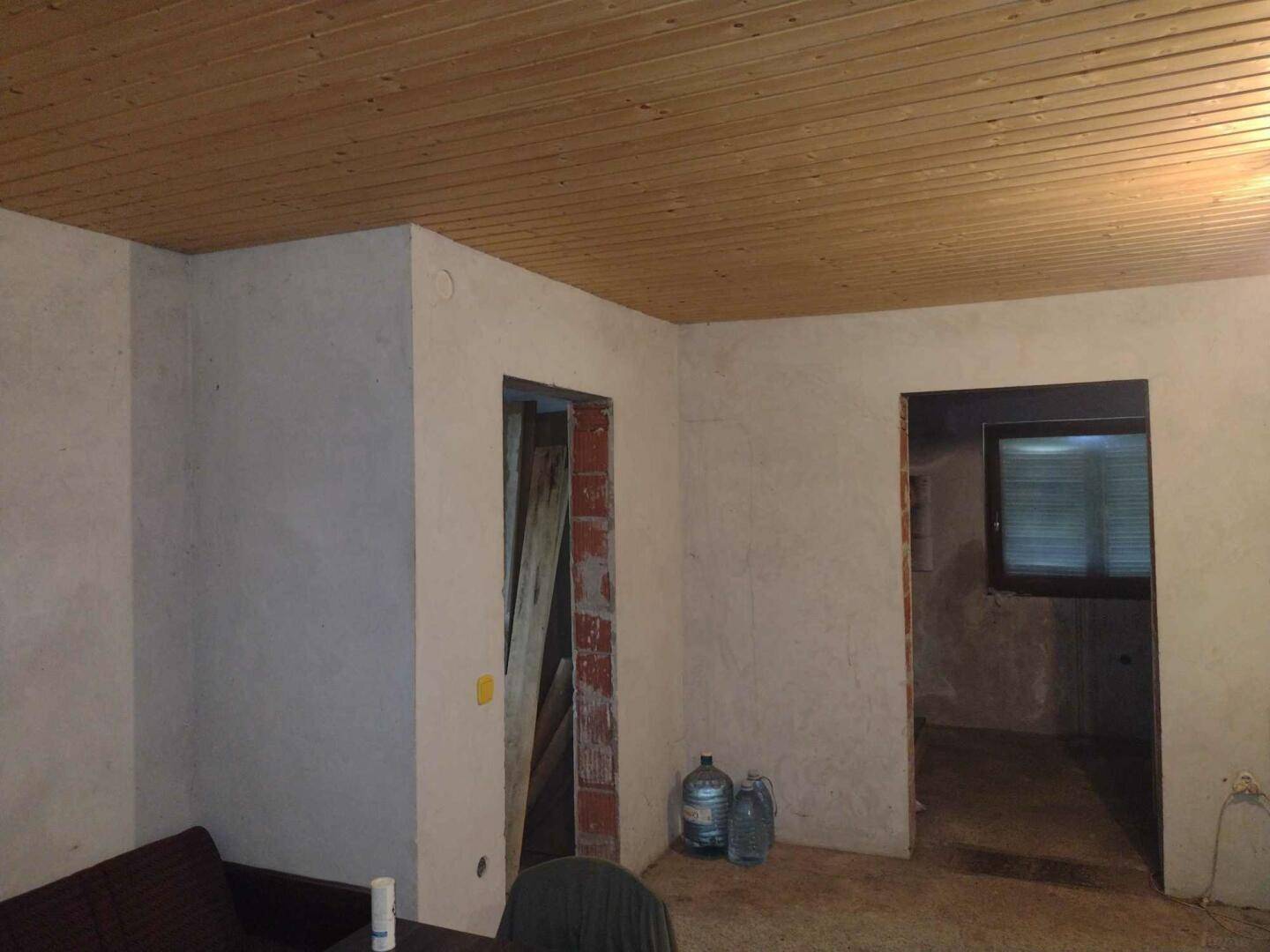 Unfertiger Raum mit einer Holzpaneeldecke und rohen Wänden, bereit für den weiteren Ausbau.