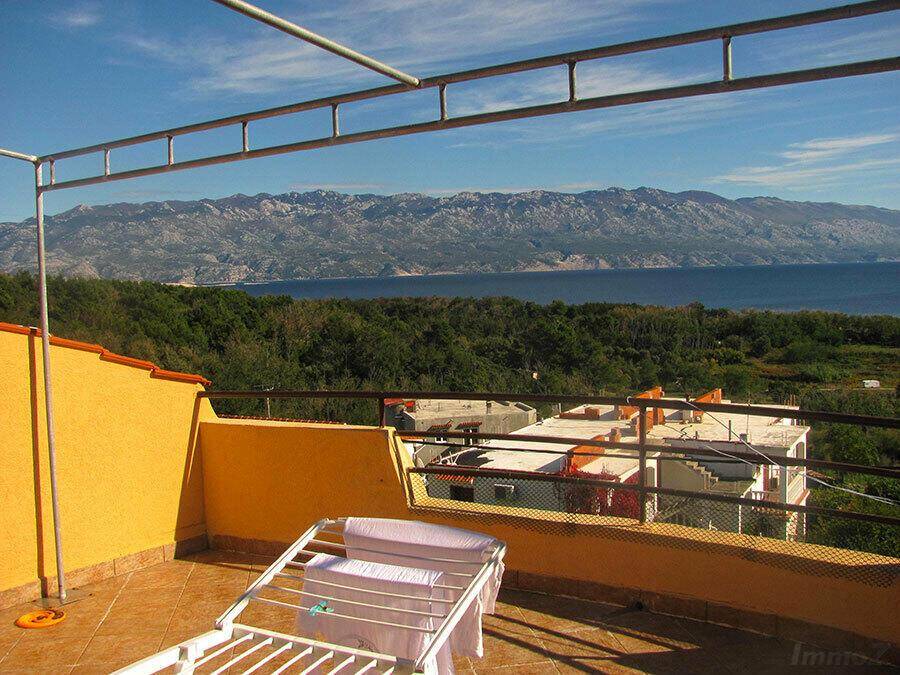 Sonniger Balkon mit Wäscheständer und Panoramablick auf das Meer und die Berge.