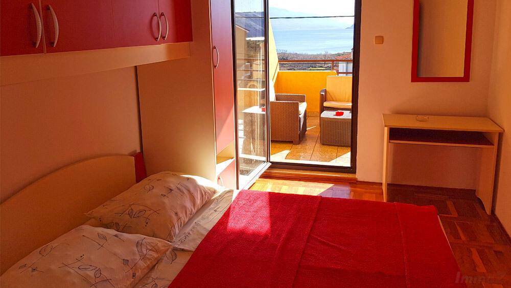 Schlafzimmer mit Zugang zu einem sonnigen Balkon und Blick auf das Meer.