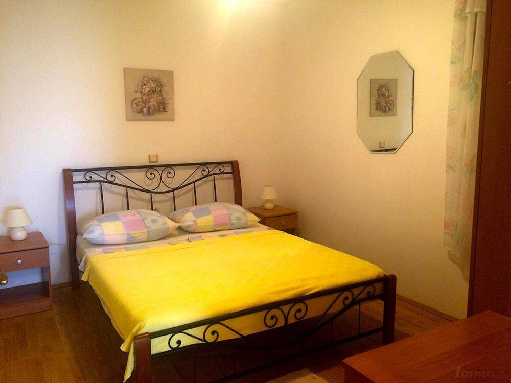 Schlafzimmer mit Doppelbett, Nachttischen und Parkettboden in hellem Ambiente.