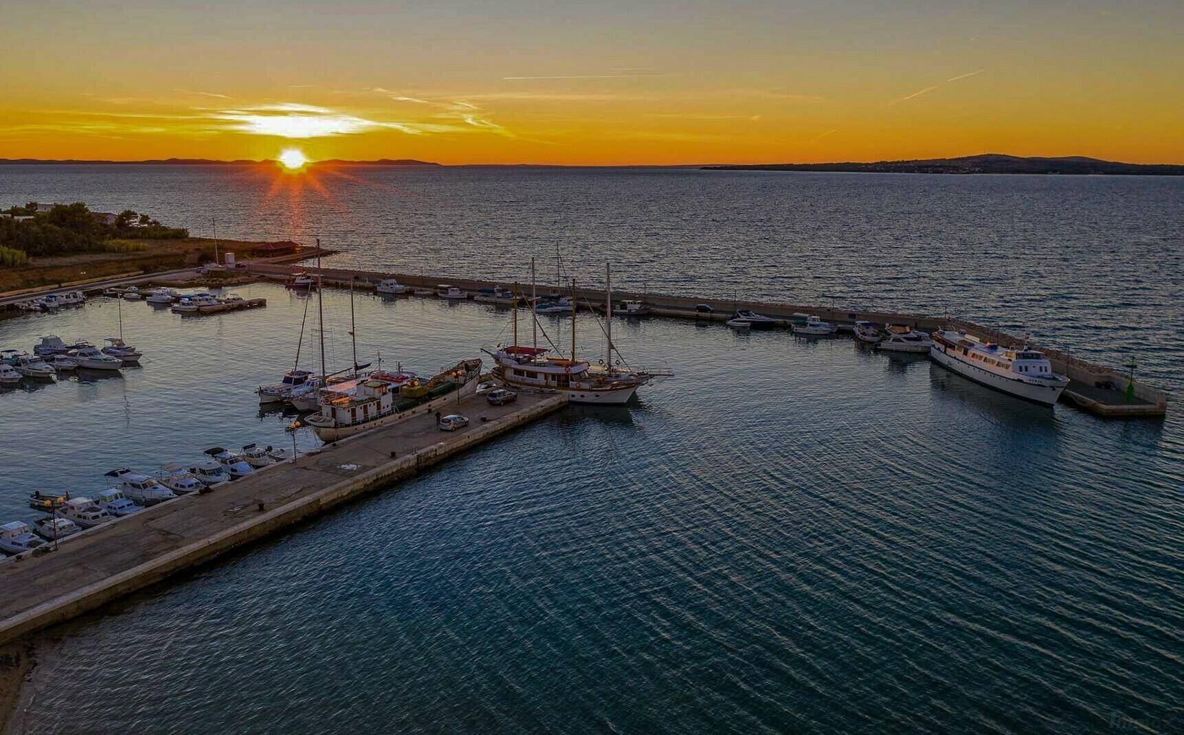 Malerischer Hafen bei Sonnenuntergang mit zahlreichen Booten und ruhigem Meer.