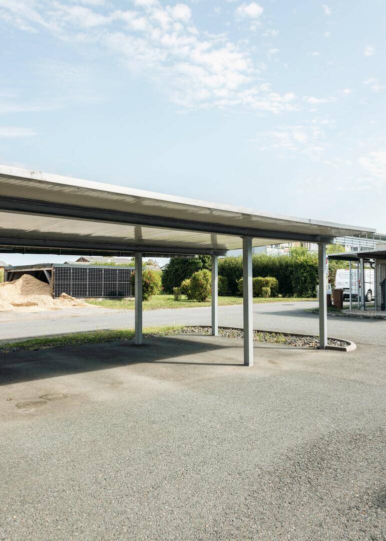 Überdachter Carport-Bereich mit mehreren Stellplätzen und angrenzender Freifläche.