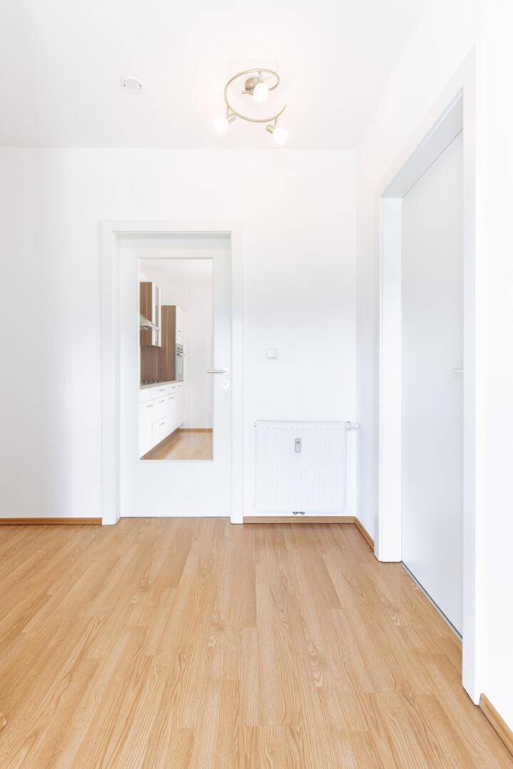 Heller Flur mit Laminatboden und weißen Türen, der zu den verschiedenen Räumen führt.
