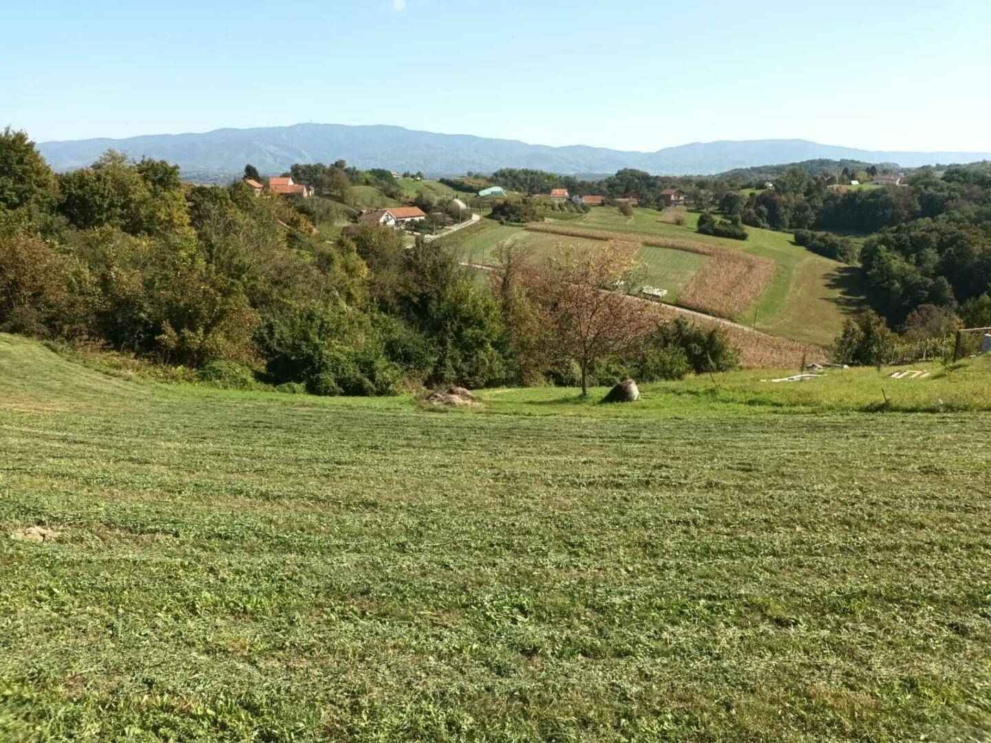 Weitläufige ländliche Landschaft mit Feldern, Wäldern und vereinzelten Häusern in der Ferne.