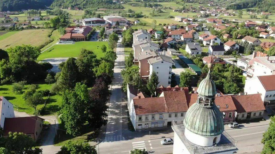Luftaufnahme einer ländlichen Stadt mit Wohngebäuden, Straßen und einer Kirche mit Kuppel.
