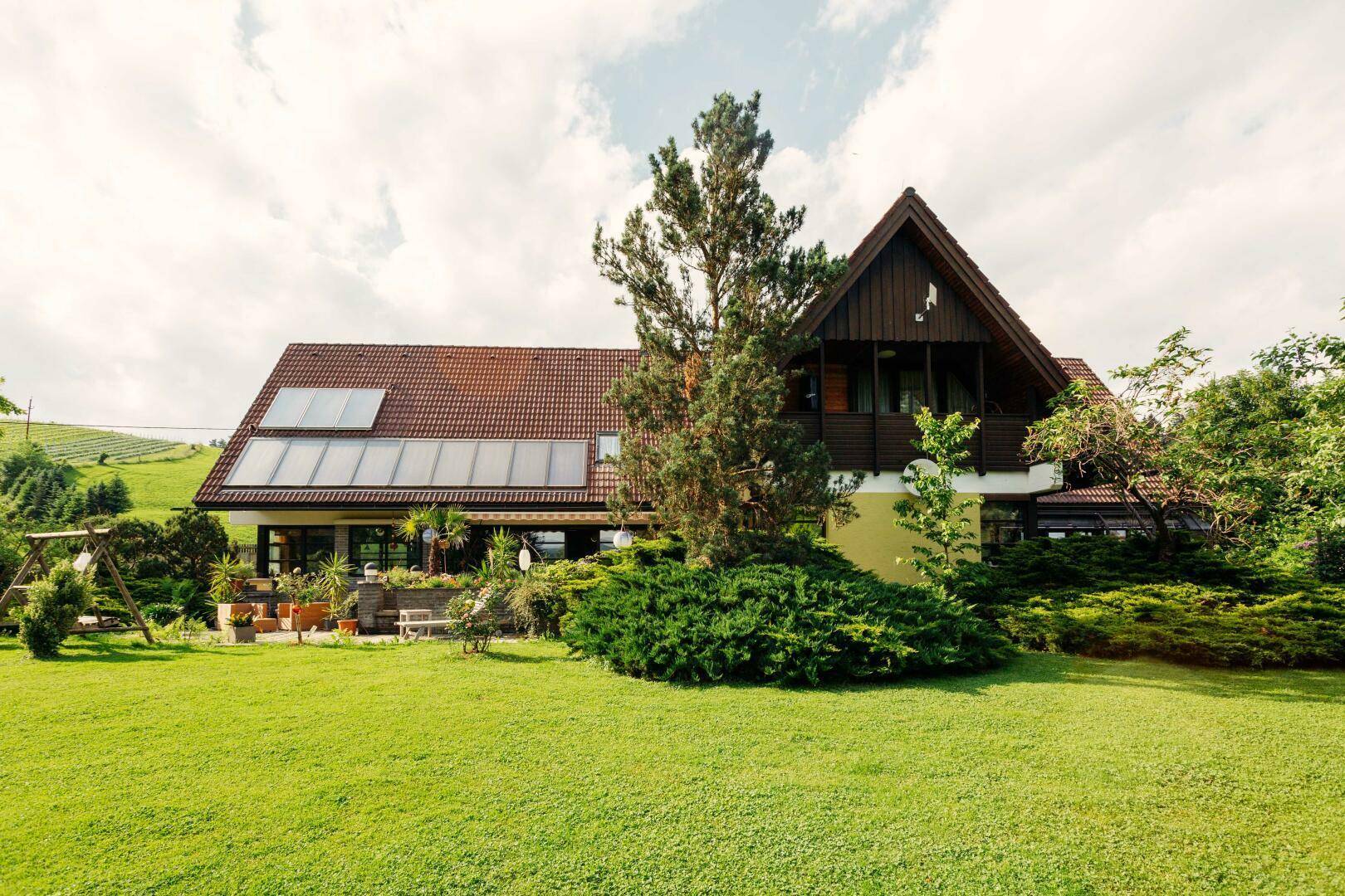 Gesamtansicht des Hauses vom Garten aus, mit Solaranlage auf dem Dach und großem Rasen.
