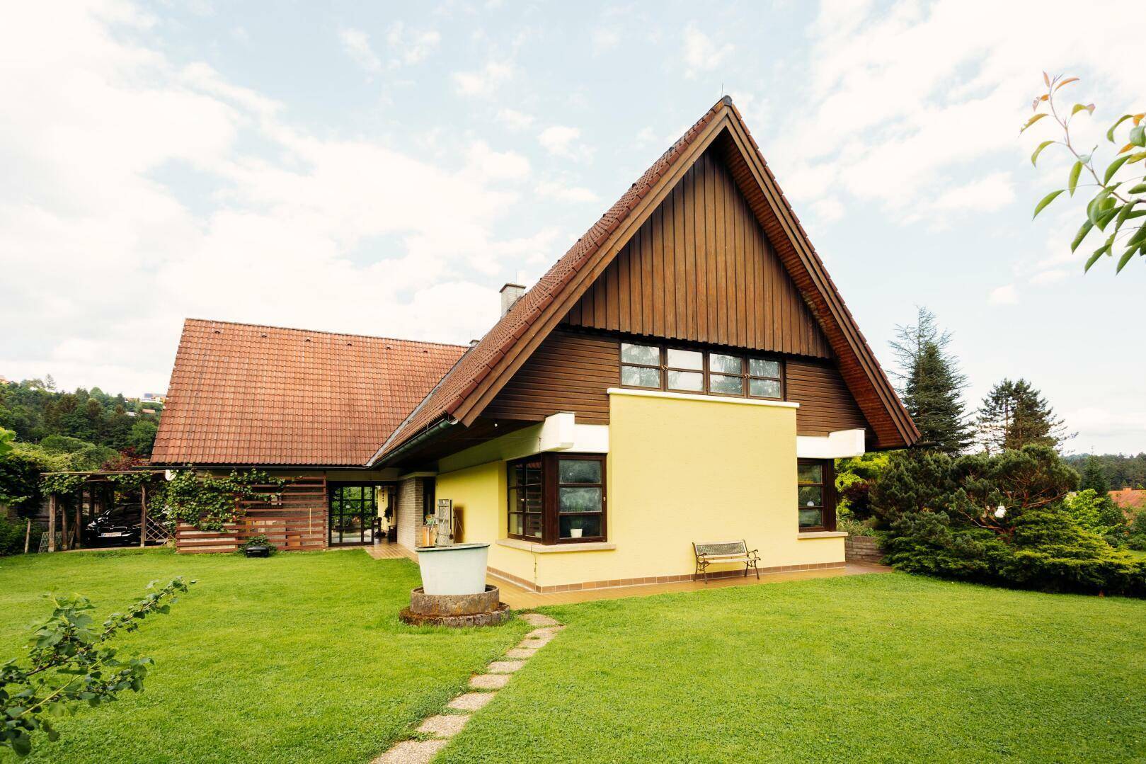 Ansicht des Hauses mit Giebeldach, gelber Fassade und weitläufigem, gepflegtem Rasen.