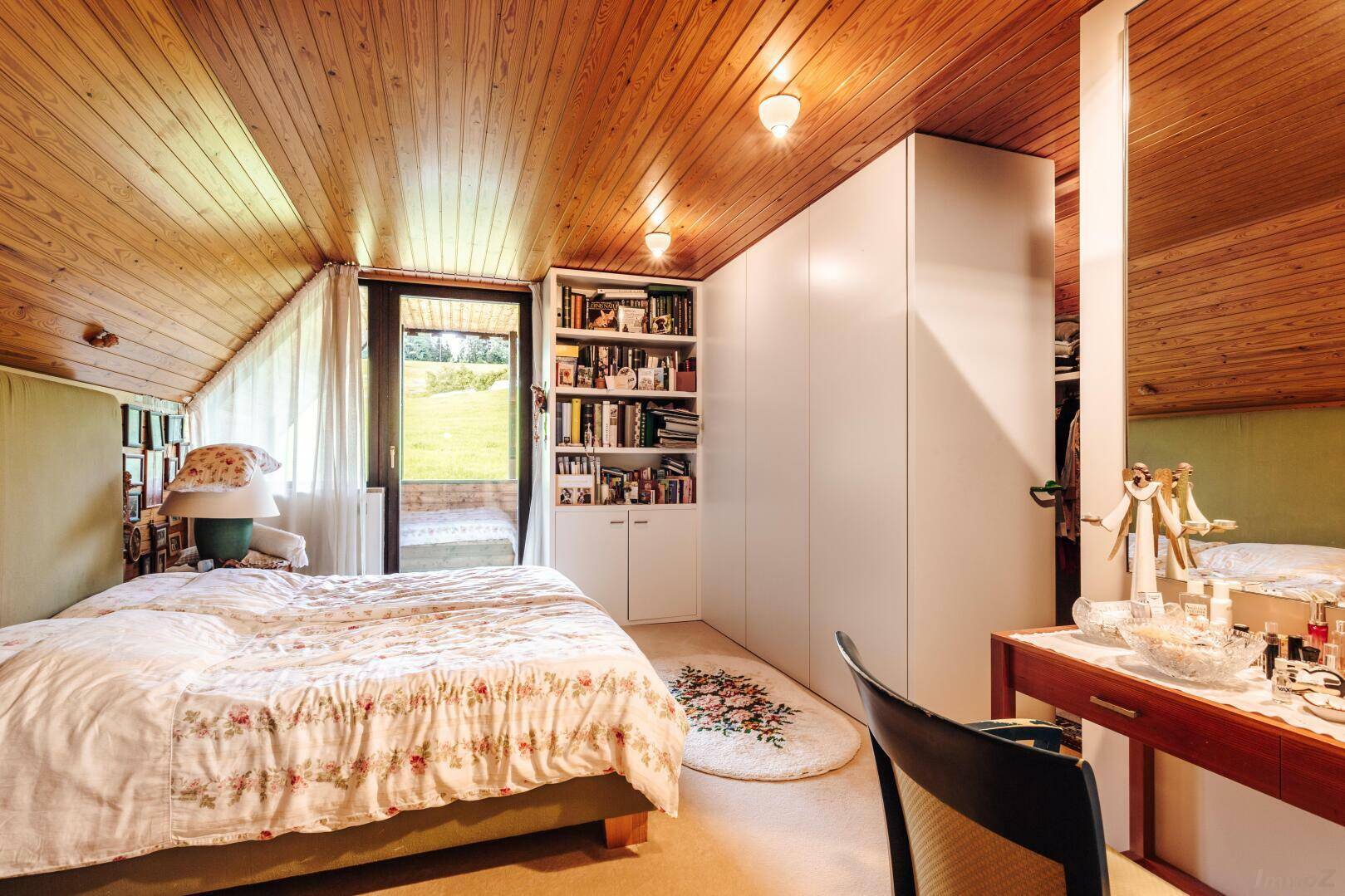 Gemütliches Schlafzimmer mit Holzdachschräge, Einbauschränken und direktem Zugang zum Garten.