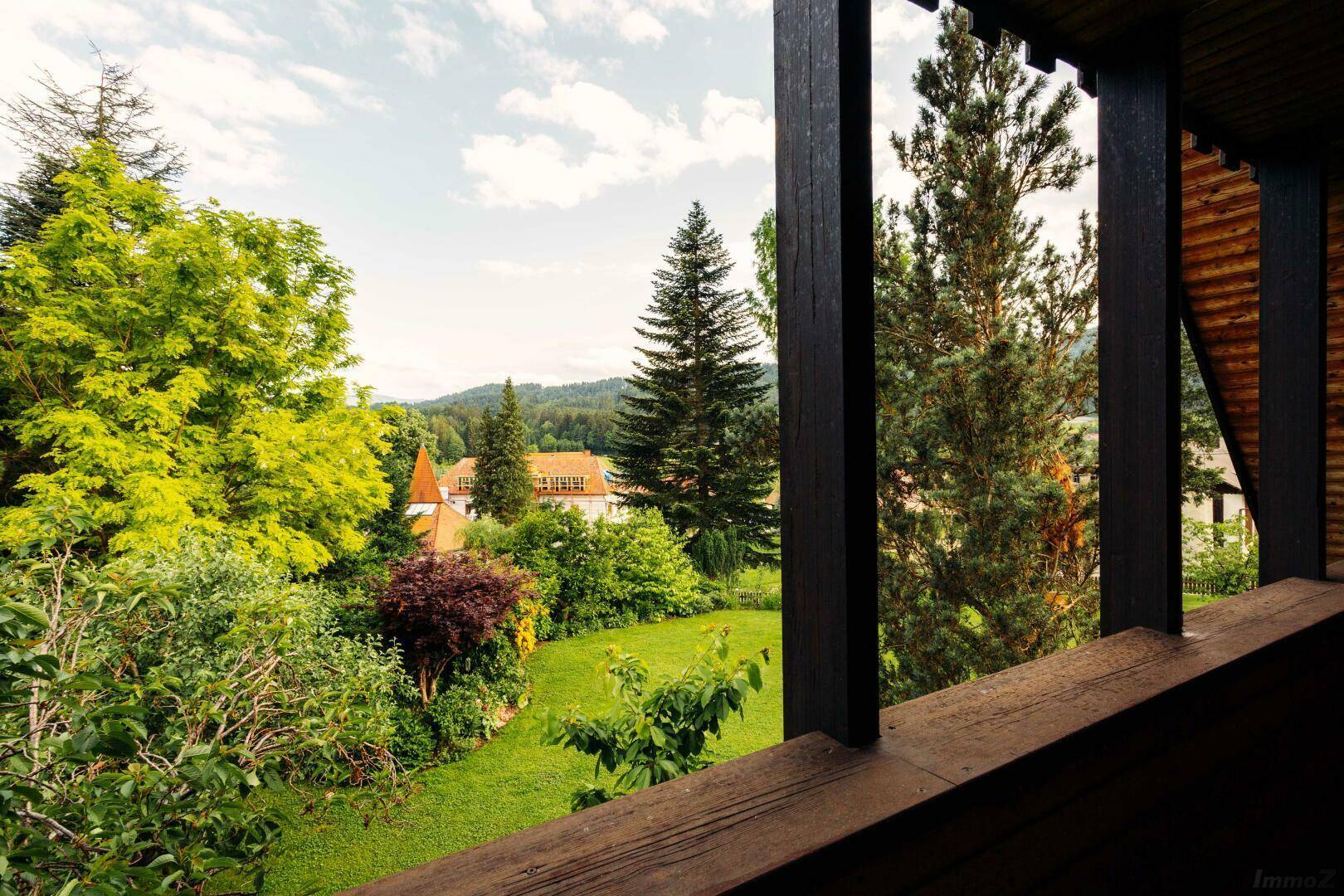 Malerischer Ausblick von einem Balkon auf einen üppigen grünen Garten und die Umgebung.