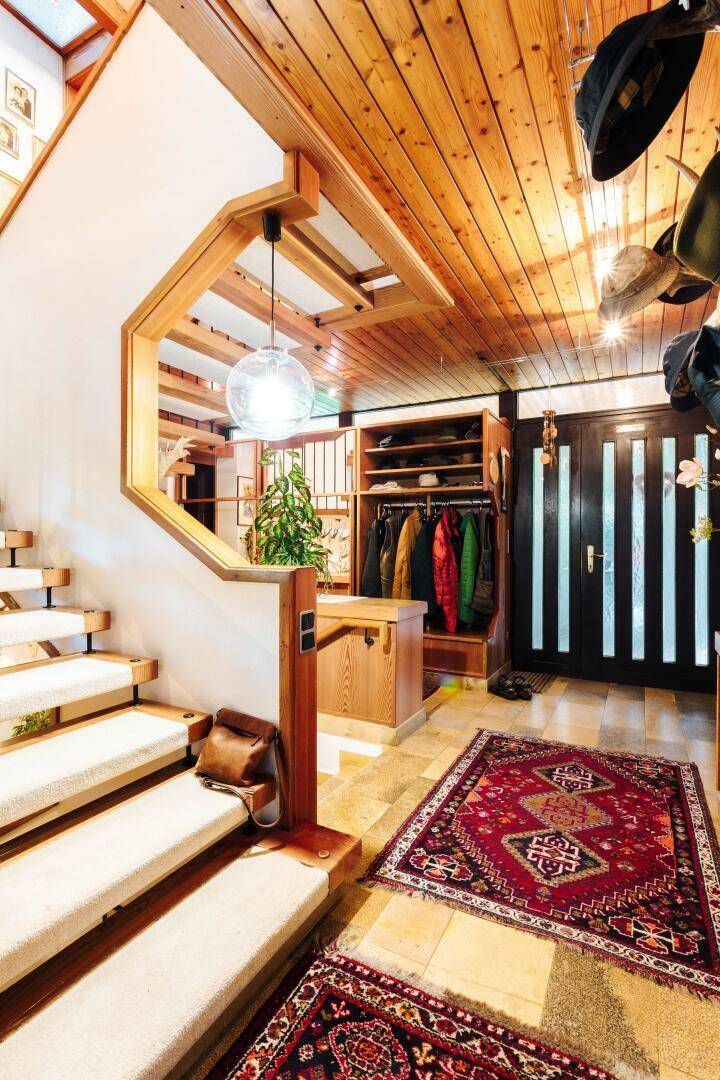 Eingangsbereich mit Teppichtreppe, Holzgeländer und integrierter Garderobe.