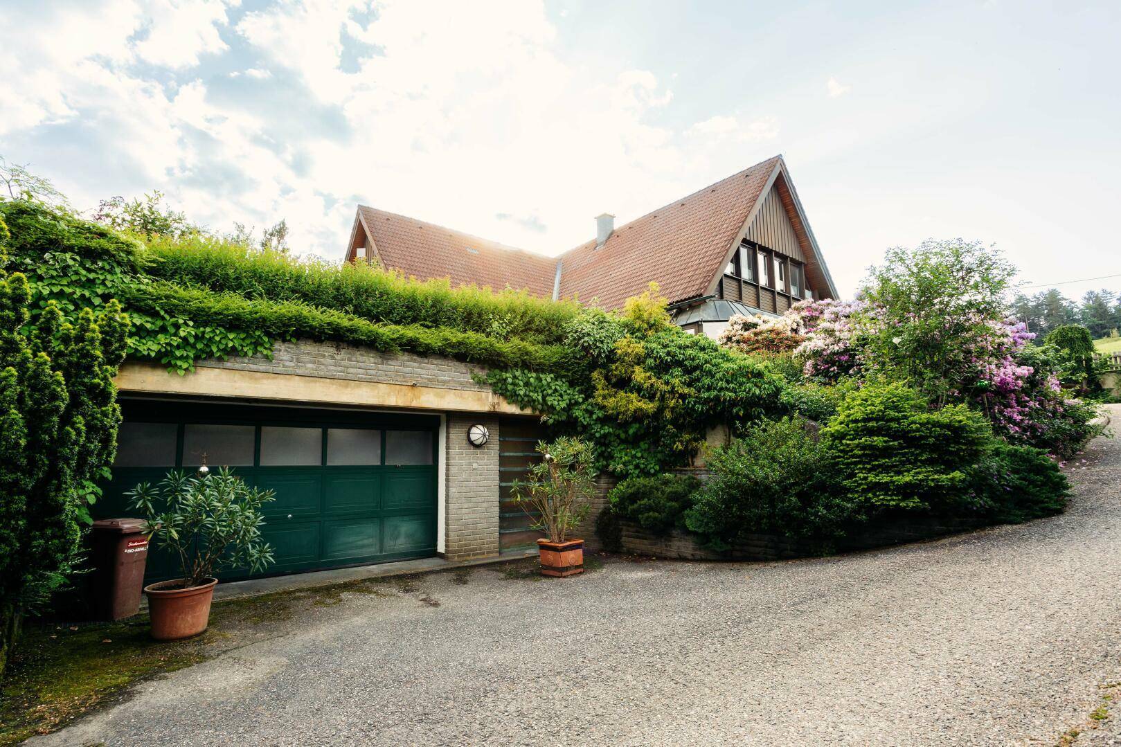 Doppelgarage mit begrüntem Dach und Zufahrt, im Hintergrund das Wohnhaus.