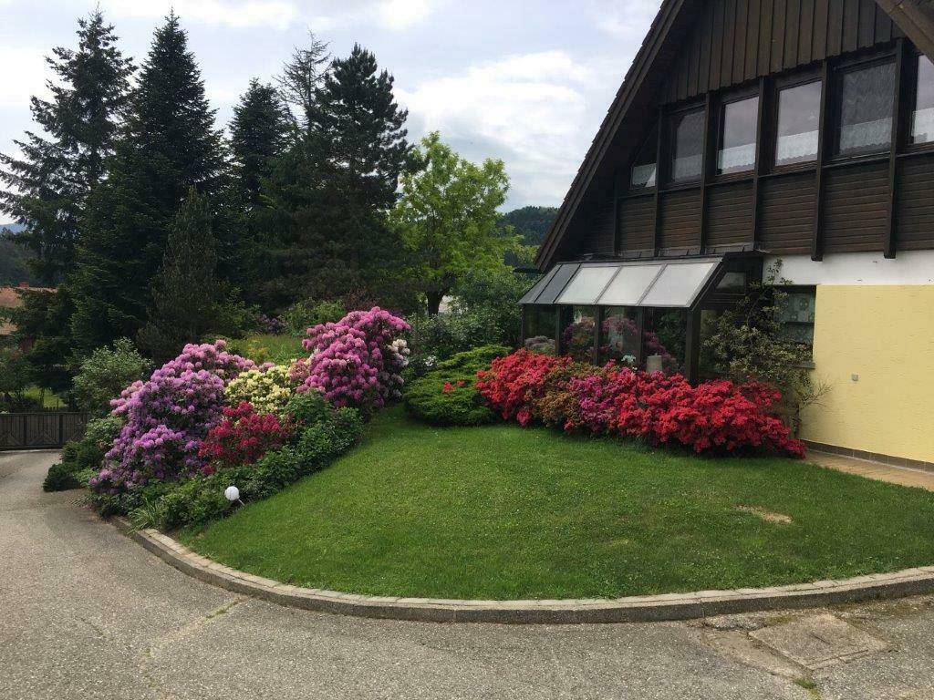 Vorderansicht des Hauses mit gepflegtem Rasen und farbenprächtigen Blumenbeeten.