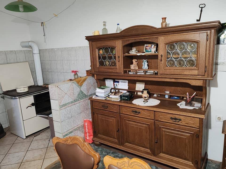 Essbereich mit traditionellem Holzschrank, Kachelofen und rustikalen Möbeln.
