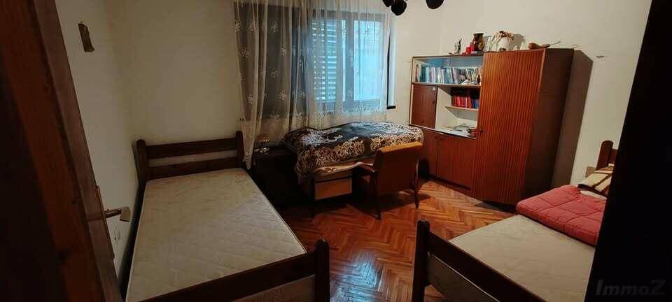 Schlafzimmer mit mehreren Betten, Holzparkett und einem Kleiderschrank.