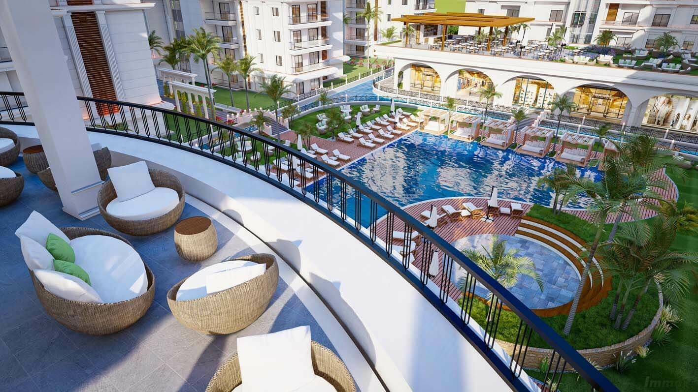 Geräumige Terrasse mit Rattanmöbeln und weitem Blick auf die Poollandschaft der Anlage.
