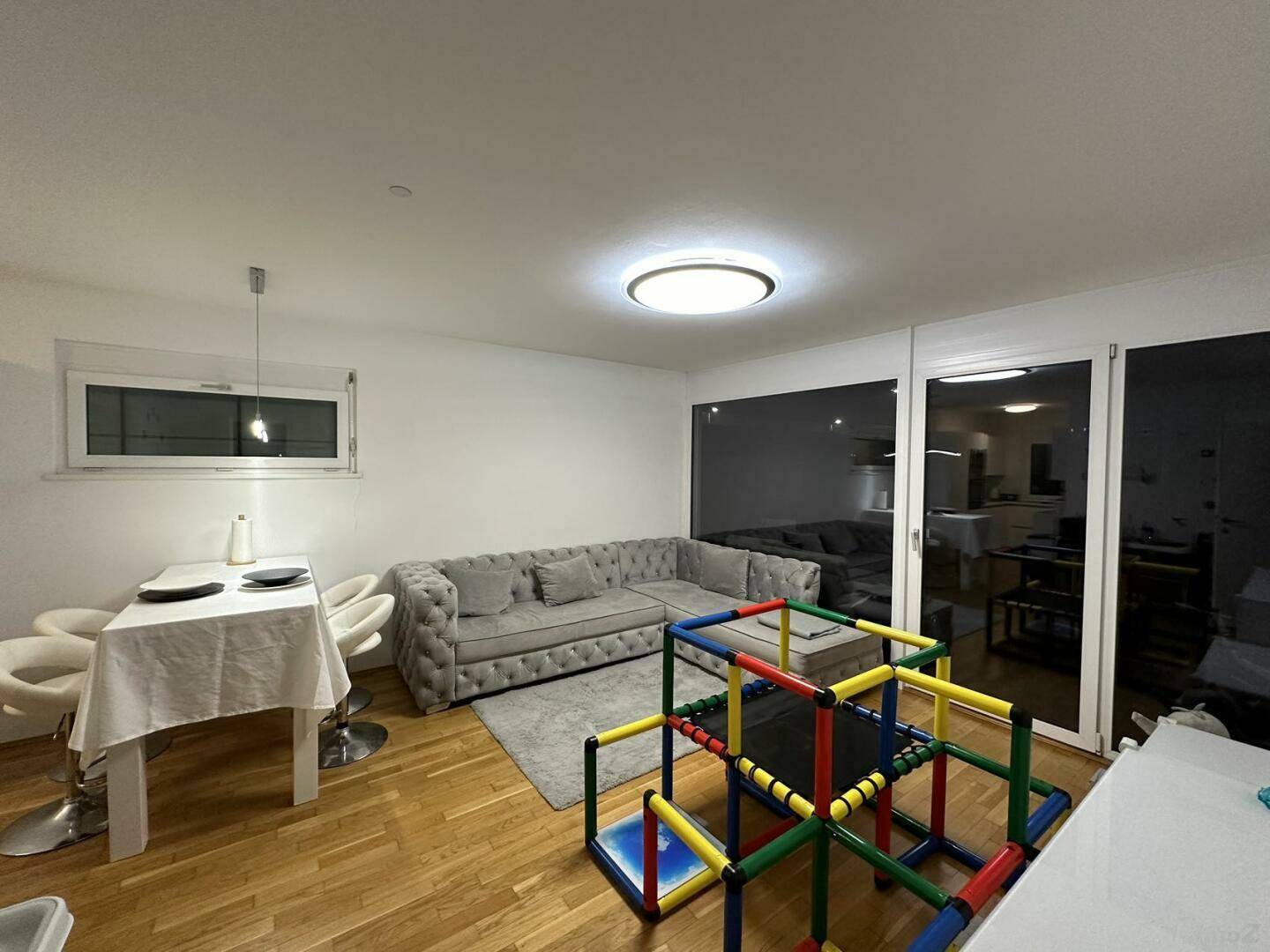 Heller Wohn- und Essbereich mit modernem Sofa, Holzboden und Zugang zur Terrasse.