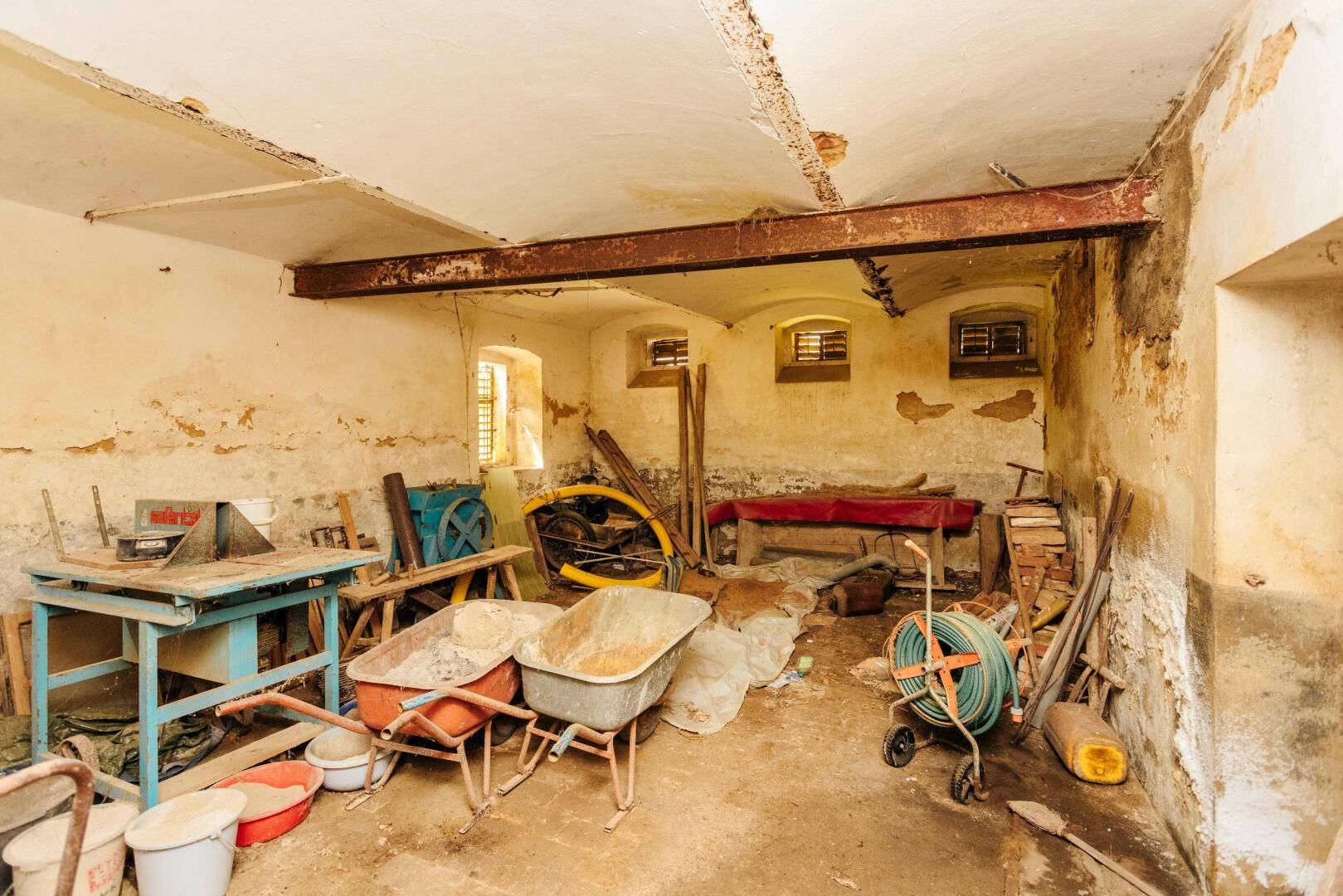 Geräumiger Kellerraum mit Werkzeugen und Baumaterialien, der auf eine Renovierung wartet.