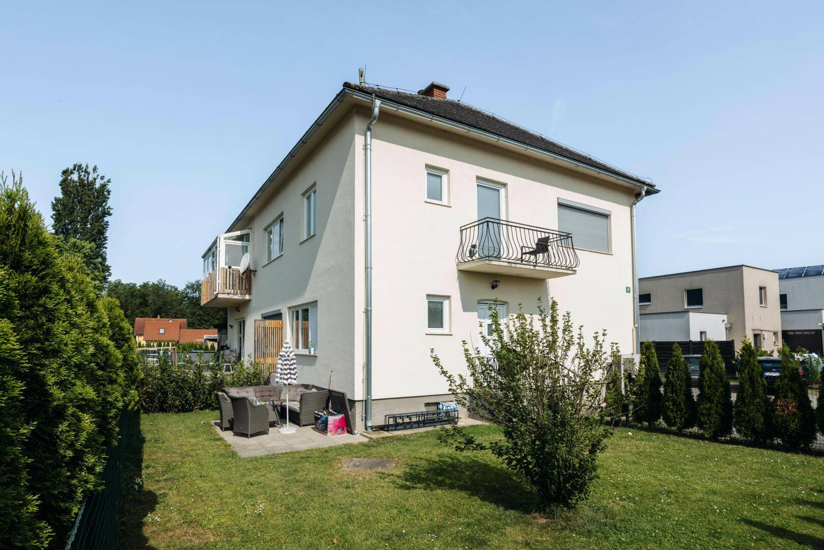 Rückansicht des Hauses mit möblierter Terrasse und großem, gepflegtem Gartenbereich.