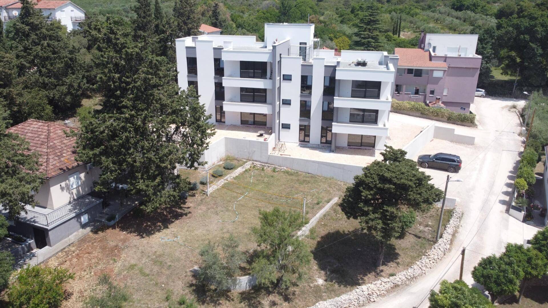 Luftaufnahme des modernen Apartmentgebäudes im Bau mit angrenzendem unbebautem Grundstück.