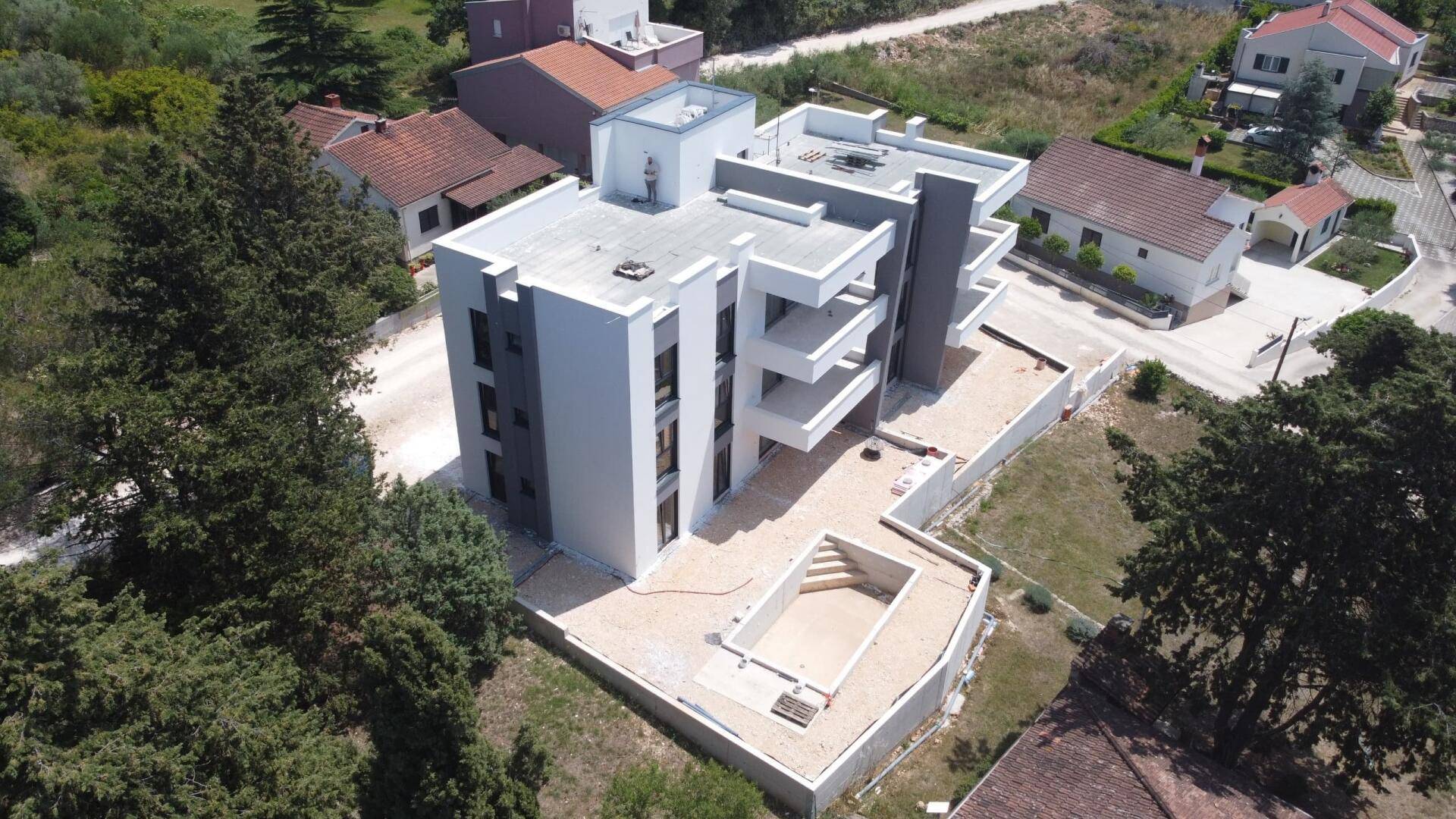 Luftaufnahme des im Bau befindlichen modernen Apartmentgebäudes mit Rohbau des Pools.