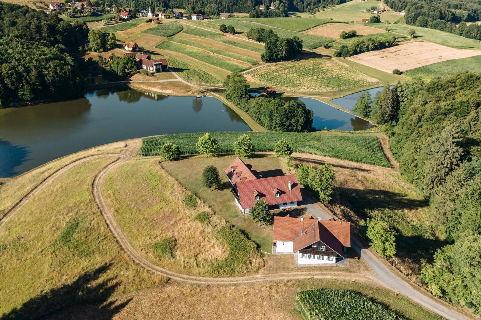 Weitläufige Luftaufnahme der Häuser in einer idyllischen Landschaft mit Seen und Feldern.