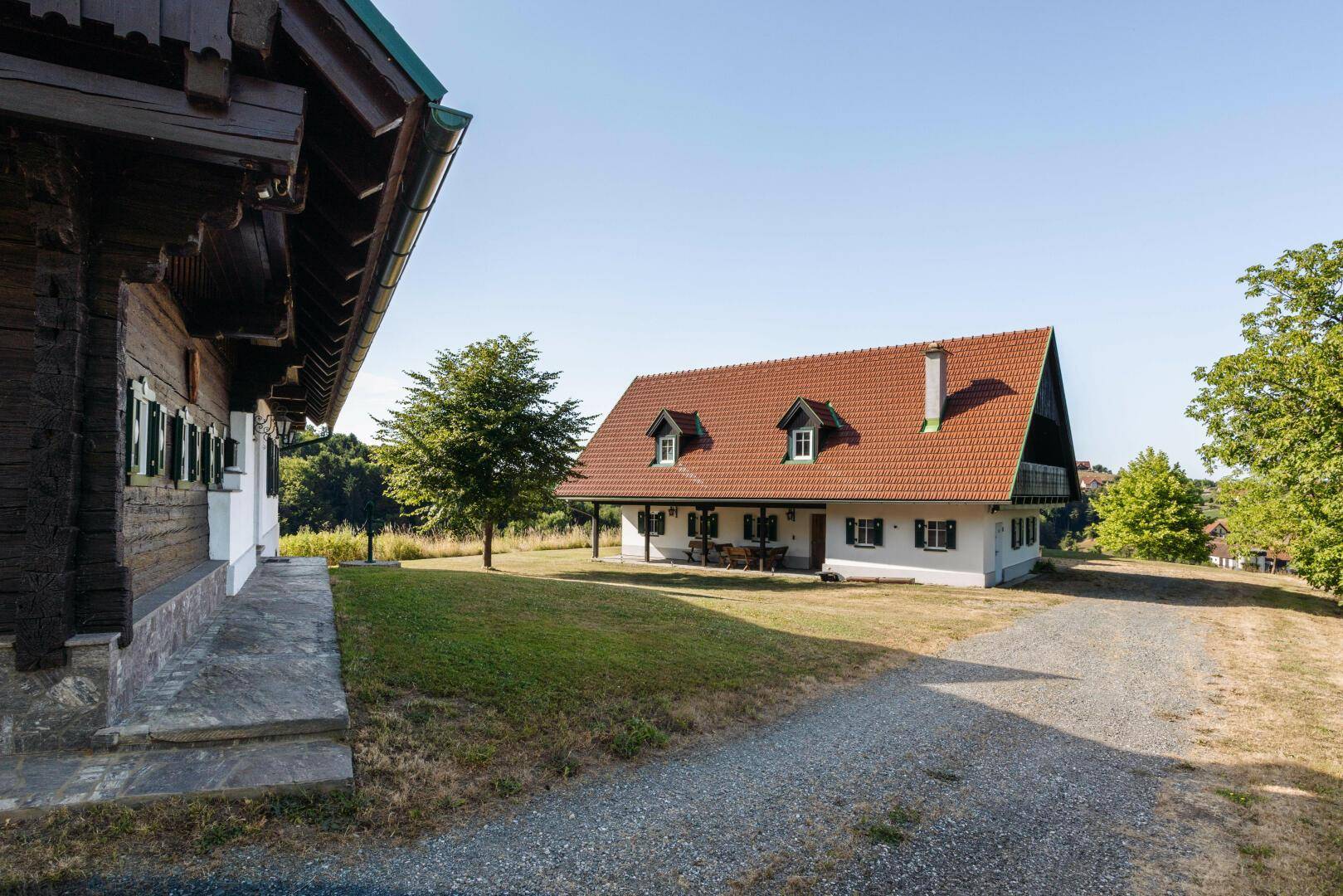 Zwei traditionelle Landhäuser mit roten Ziegeldächern und gepflegtem Vorgarten in sonniger Lage.