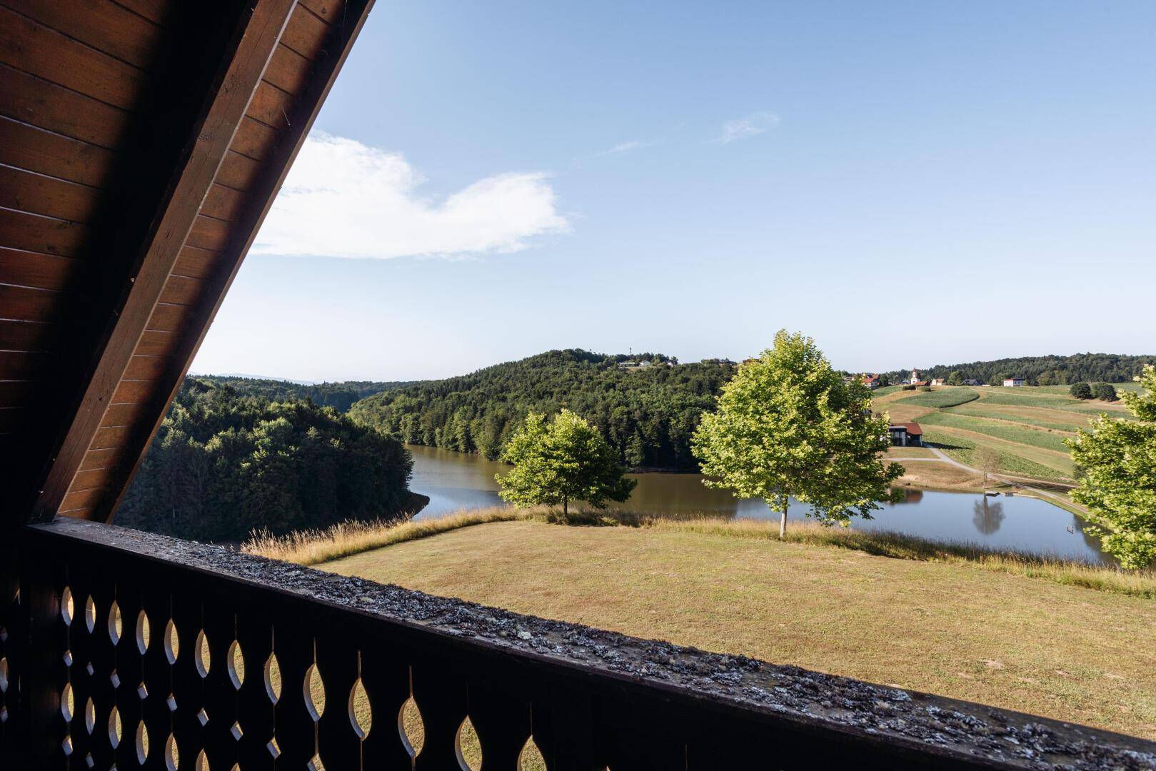 Weitläufiger Blick vom Balkon über den See, die Wälder und die sanften Hügel der Umgebung.