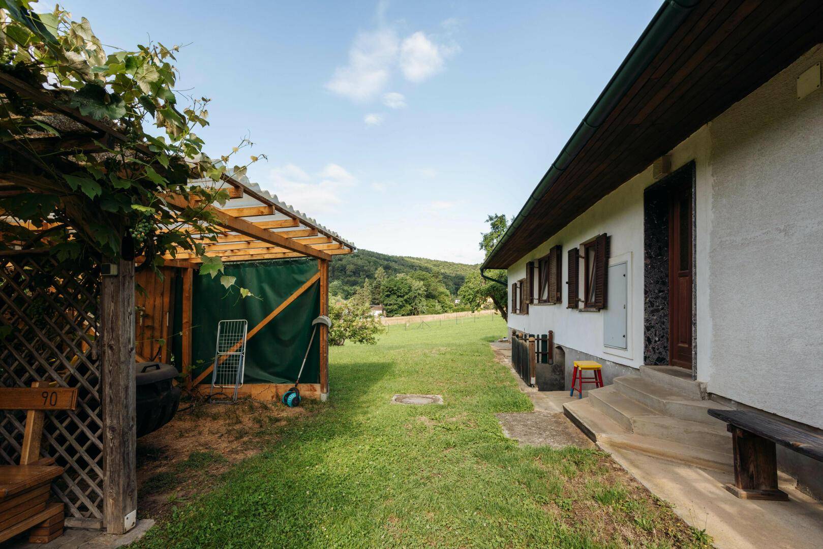 Seitenansicht des Hauses mit Holzkonstruktion und weitem Blick ins Grüne.