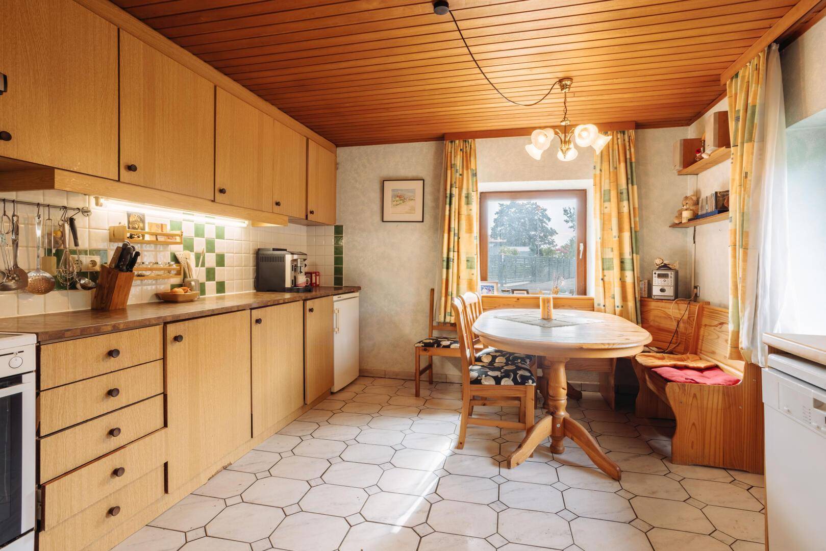 Traditionelle Küche mit Holzschränken, Fliesenboden und integrierter Essecke.
