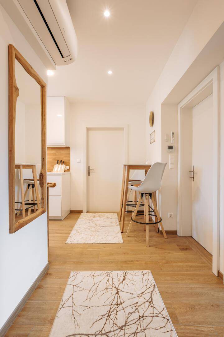 Heller Flur mit Holzspiegel, Garderobe und Blick in die moderne Küche.